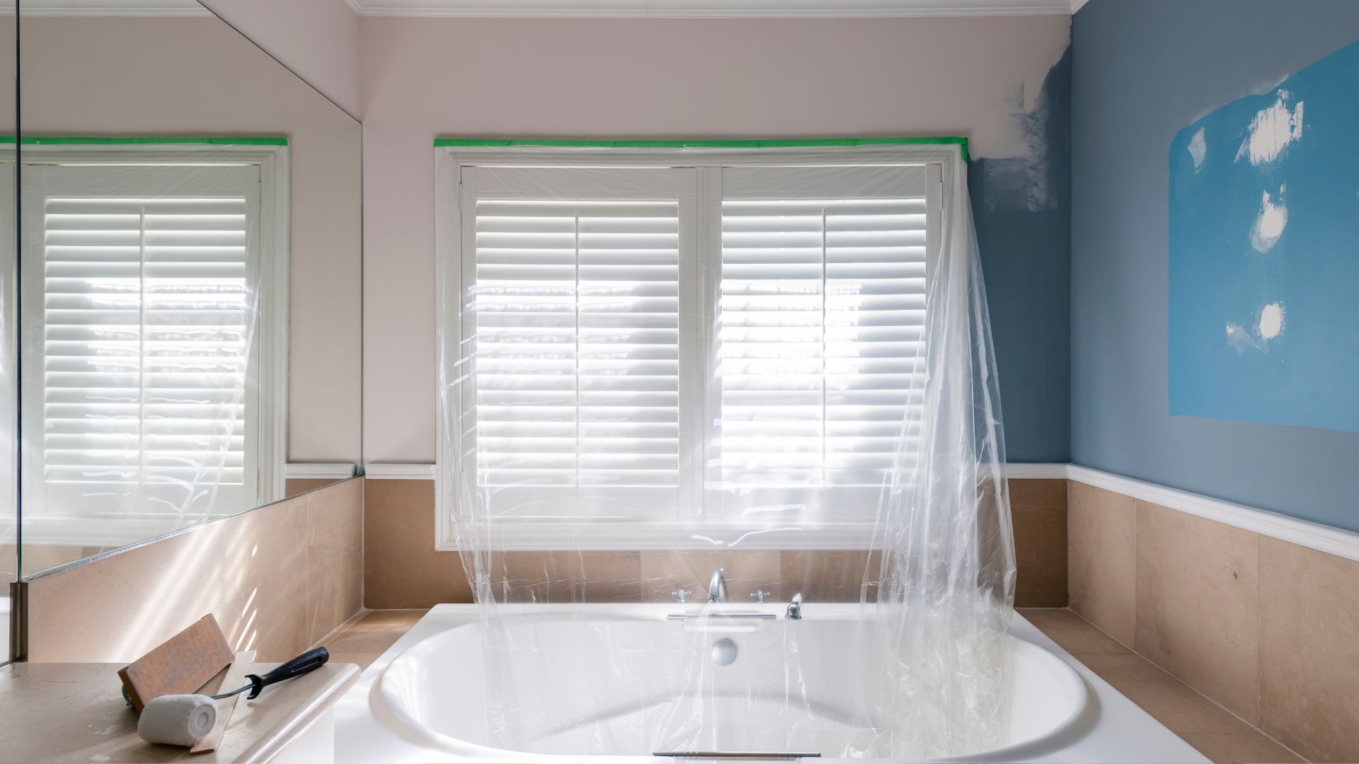 A white bath tub sitting under a bathroom window