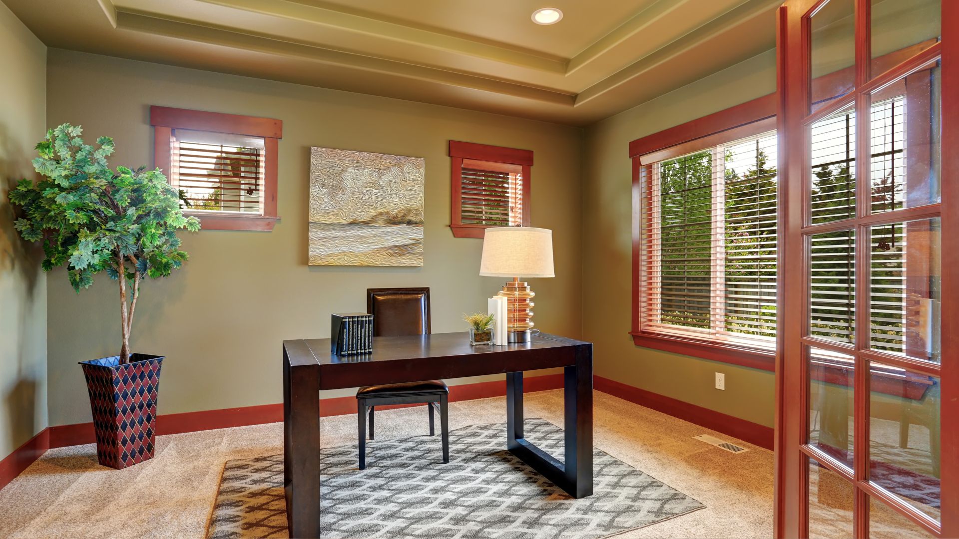 A home office with a desk, lamp, and pictures on the wall