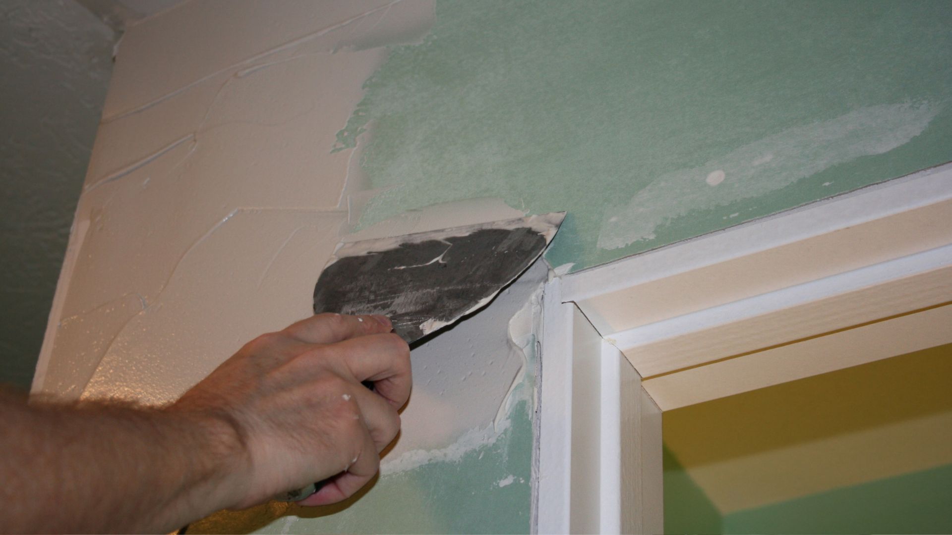 A person painting a wall with a paint roller