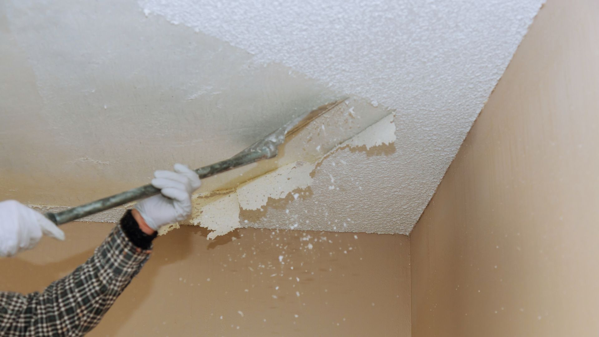 A man in white gloves and white gloves painting a ceiling