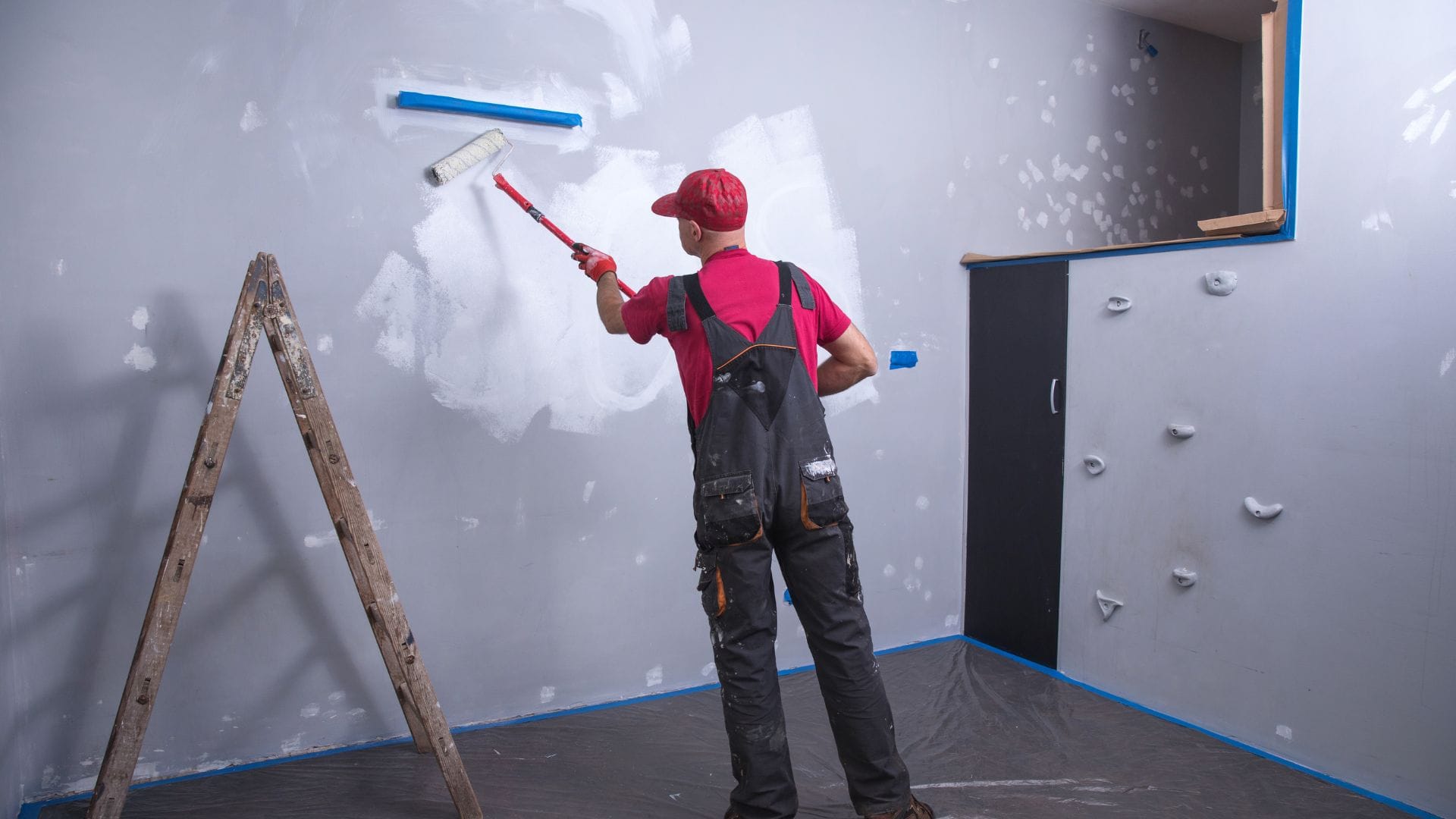 Painter rolling primer over freshly patched drywall in a bedroom