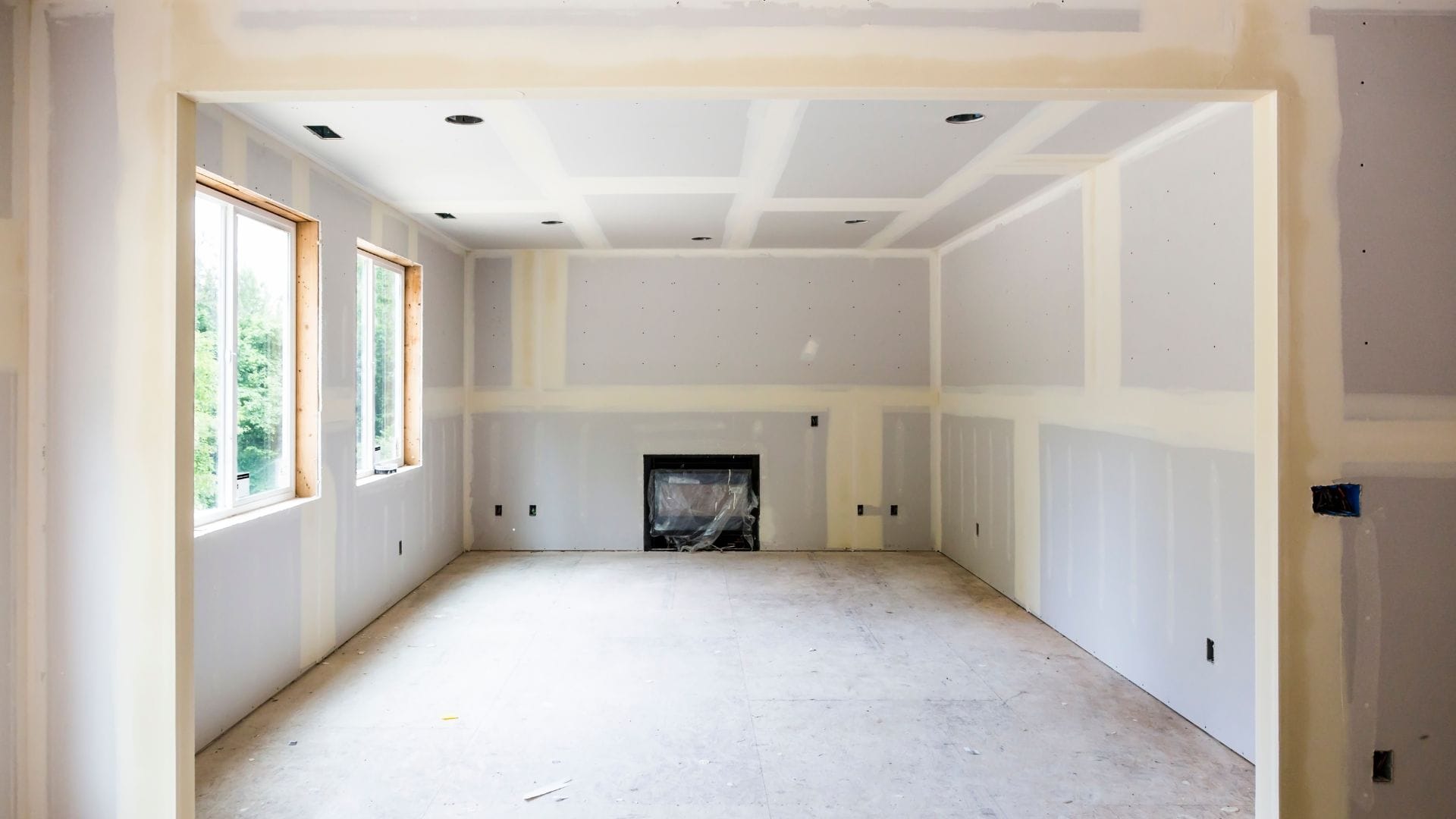 Living room with new drywall taped and mudded, ready for sanding