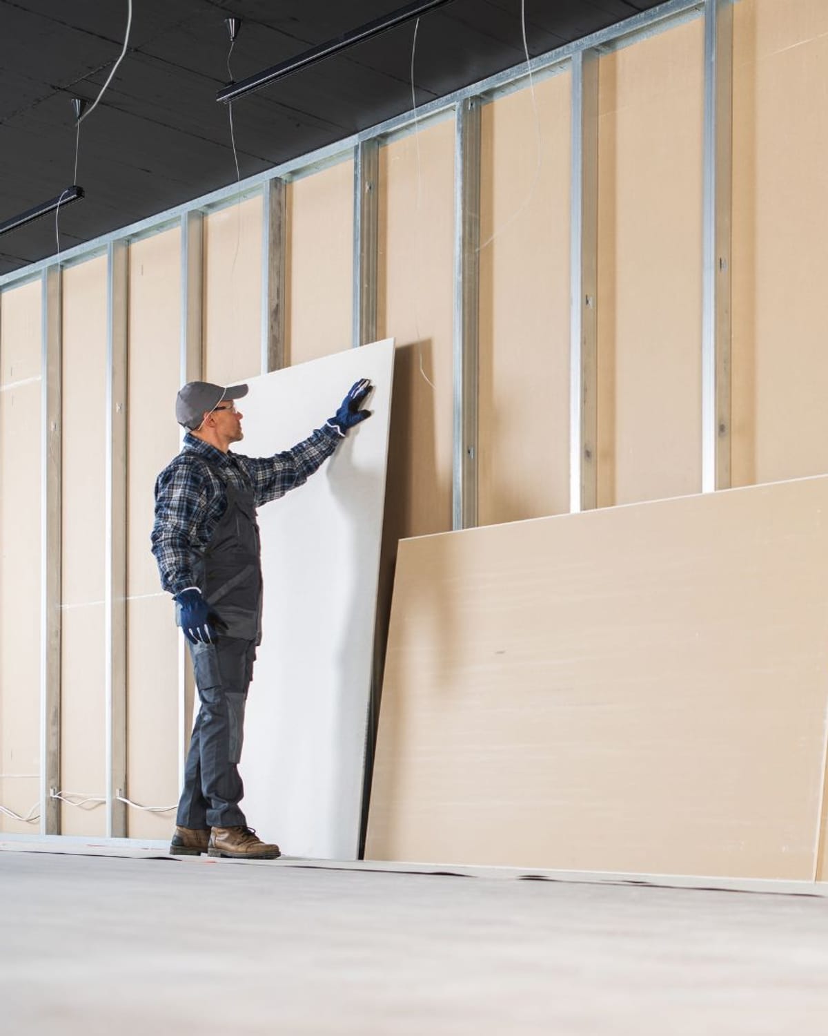 Sheets of drywall staged against metal framing in a room being finished
