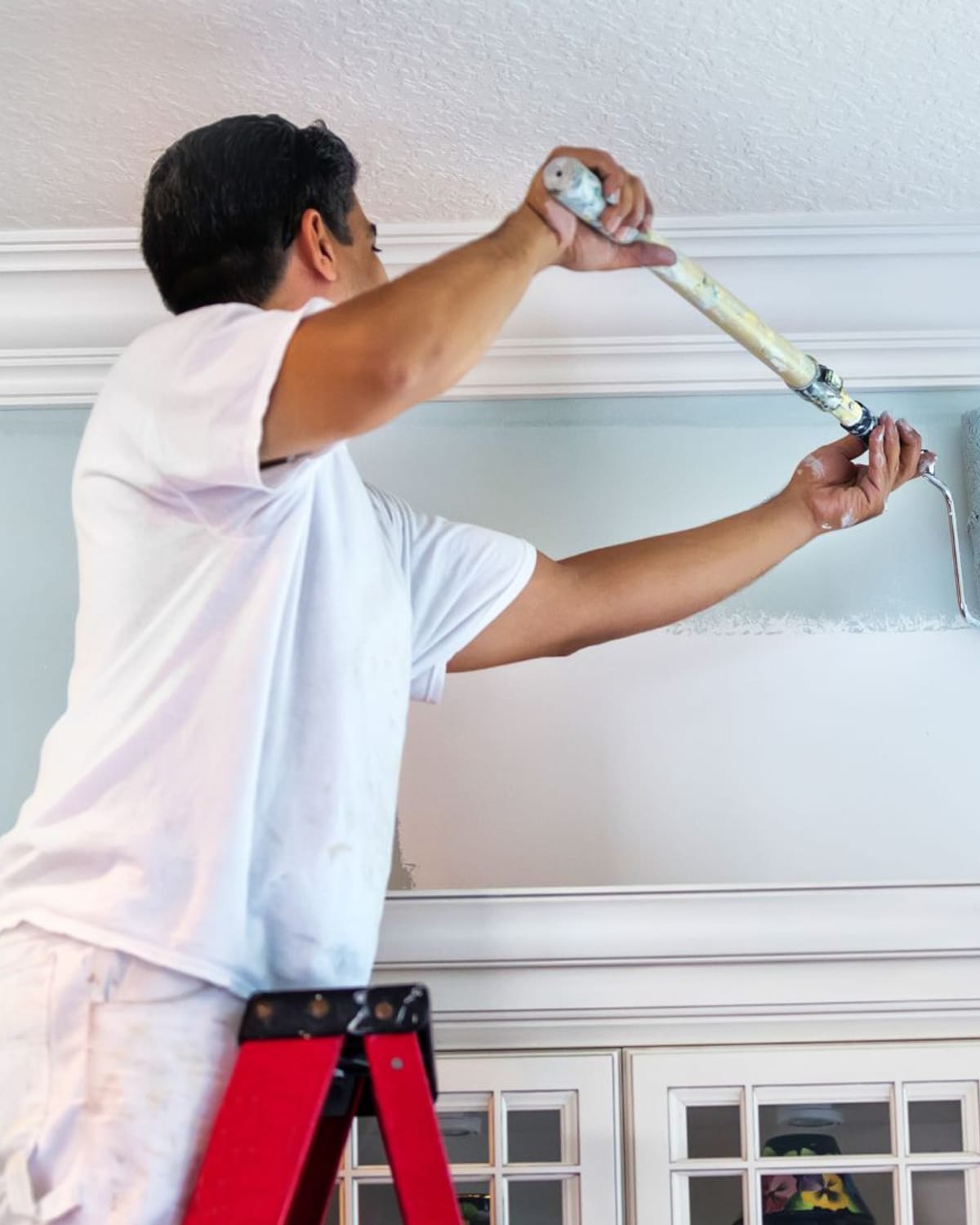 Painter rolling a fresh coat beneath crown molding in a Great Falls, MT living room