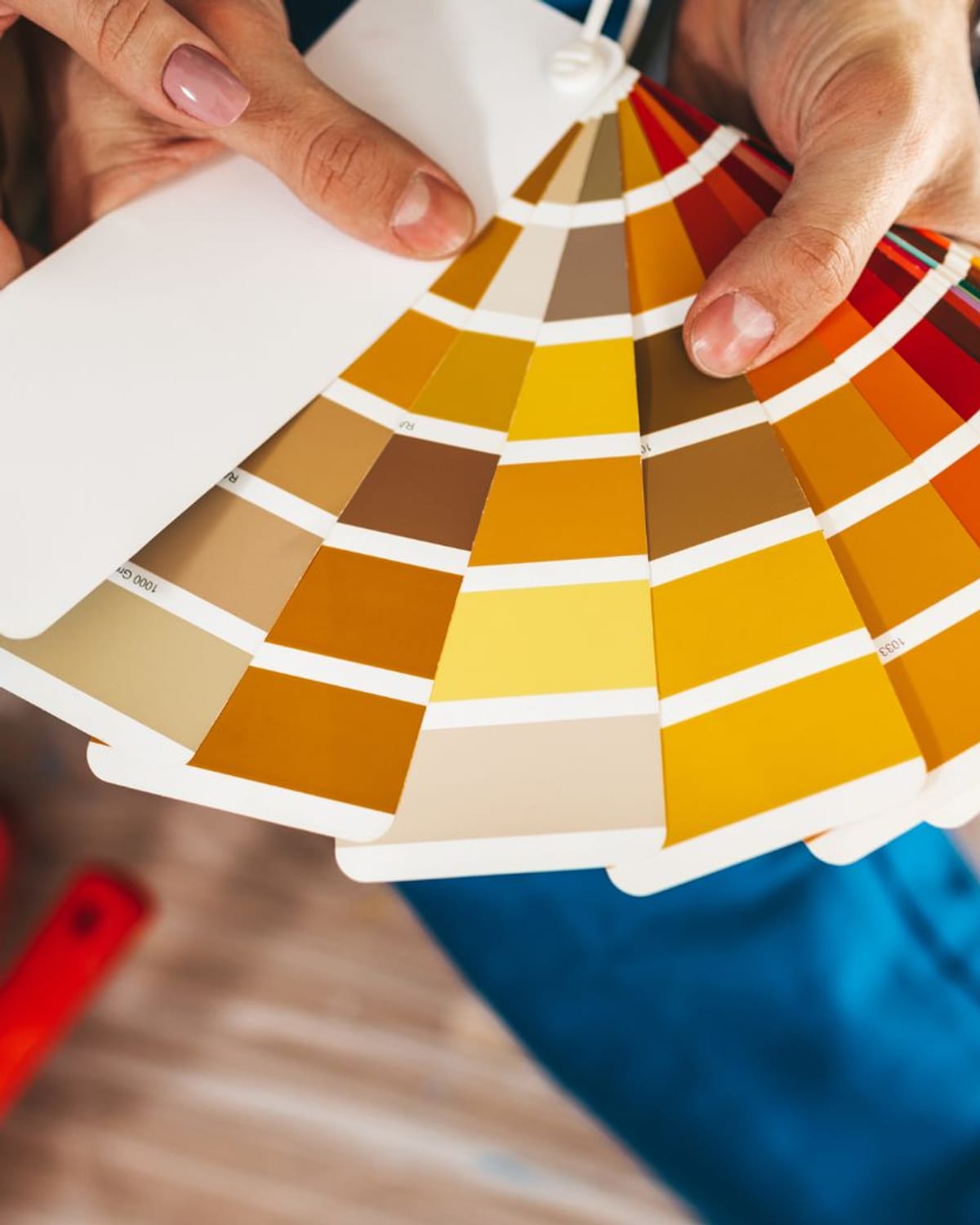Hands fanning a paint color deck over a roller tray during a color consultation