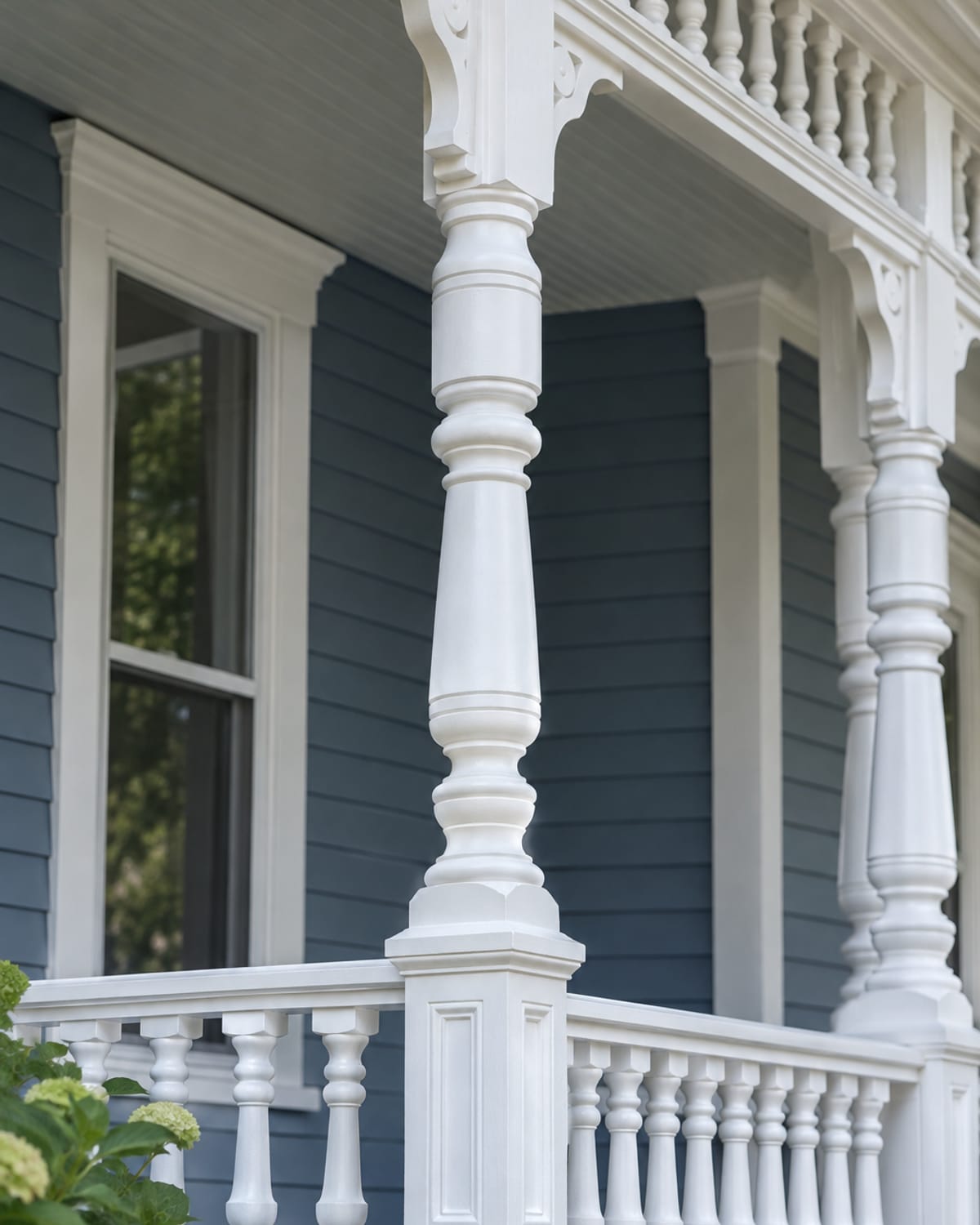 Freshly painted white Victorian porch trim and turned spindles against a slate-blue house in Fort Benton, MT