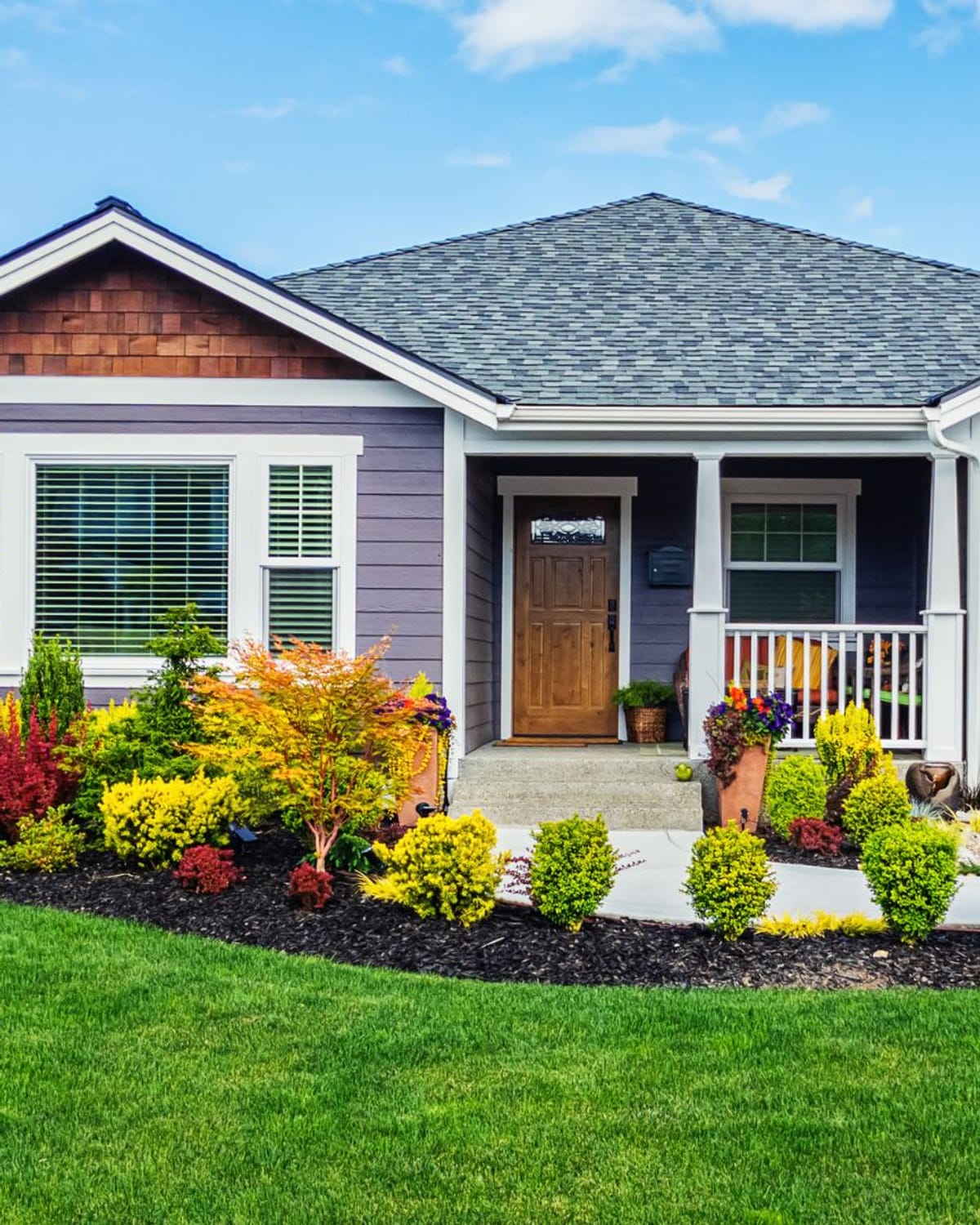 Well-kept bungalow with freshly painted lavender siding and white trim on a sunny day