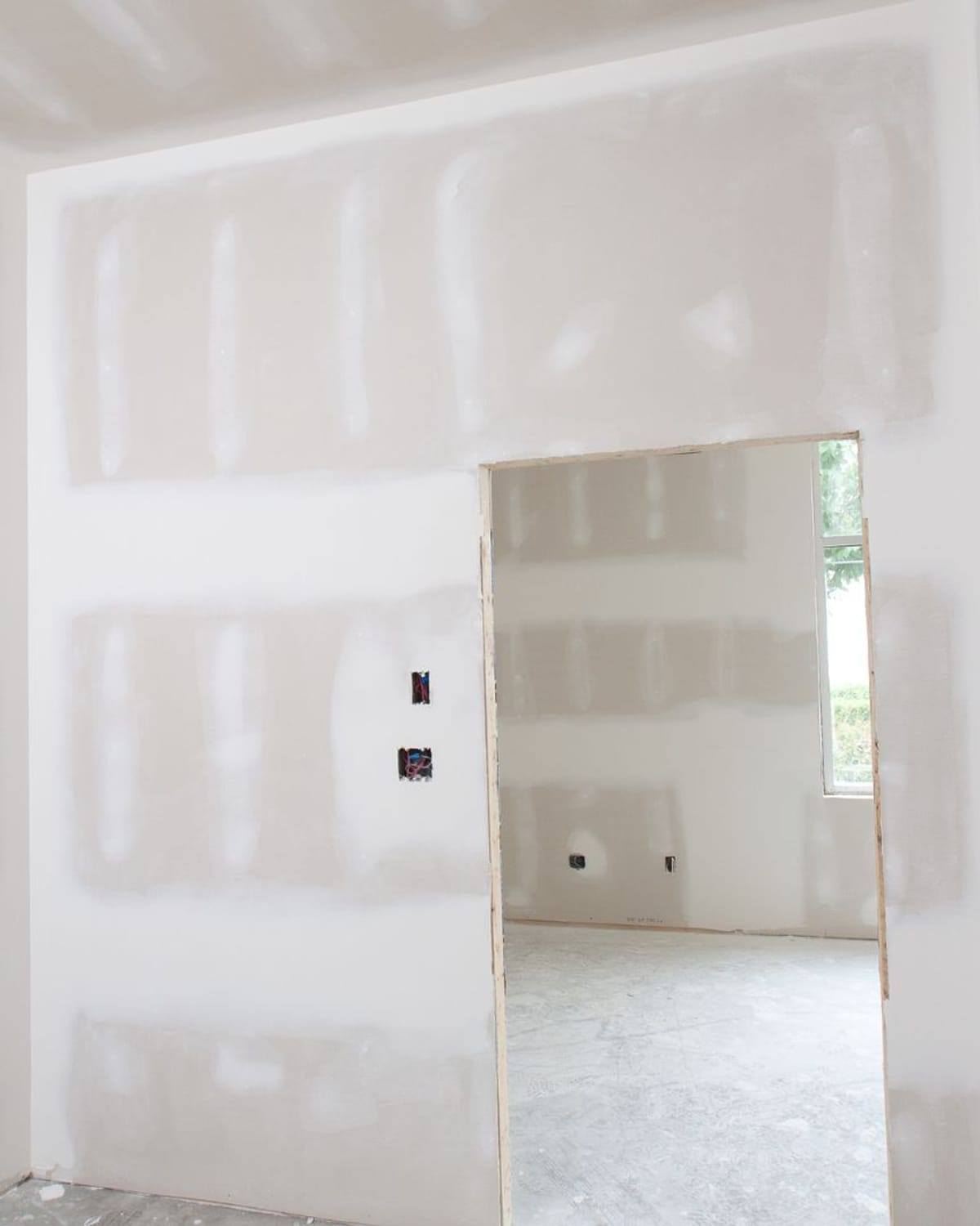 Freshly taped and mudded drywall seams around a doorway in a basement finish