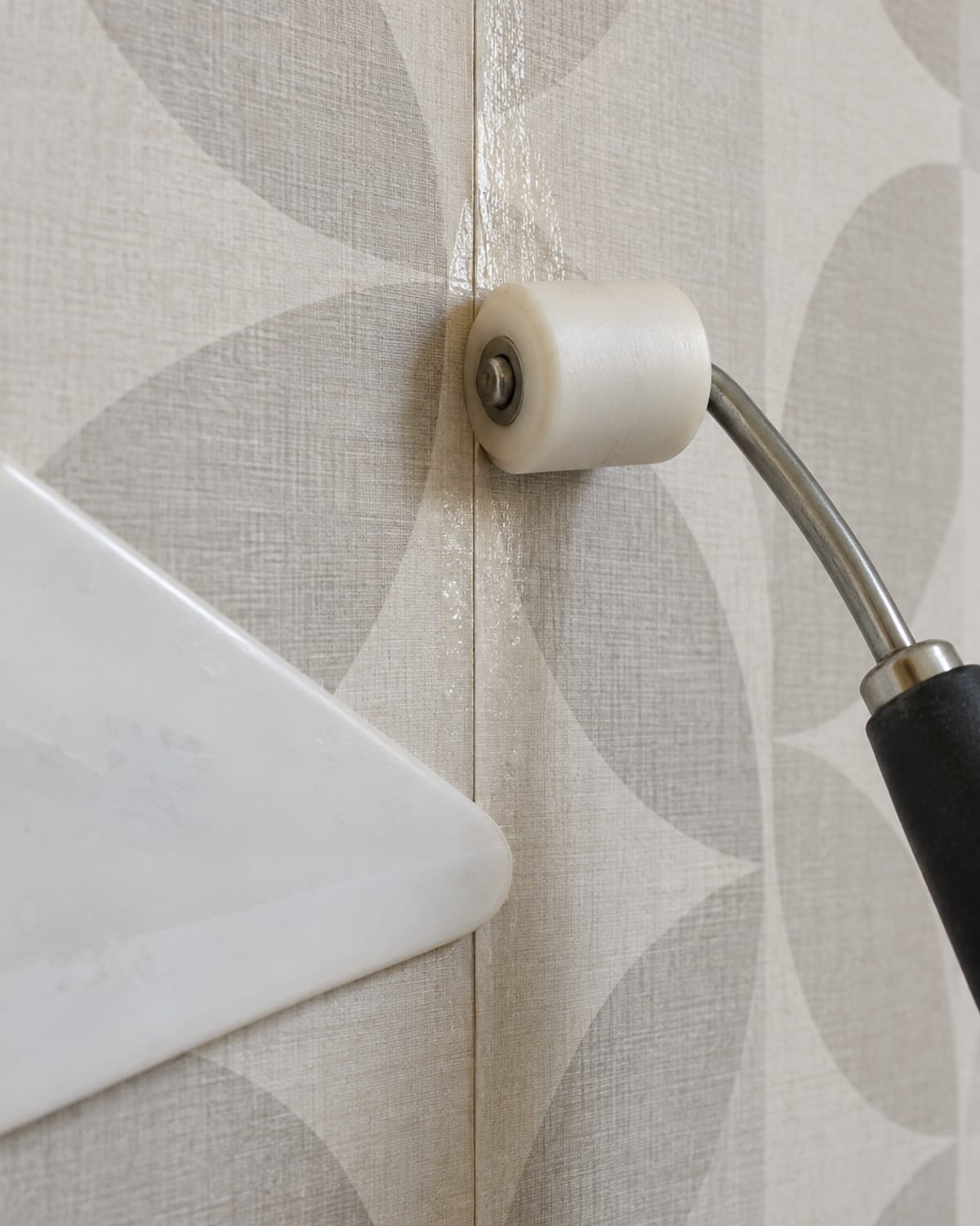 Seam roller and smoothing tool pressing a wallpaper seam flat during installation